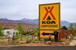 KOA sign with couple pointing to campground