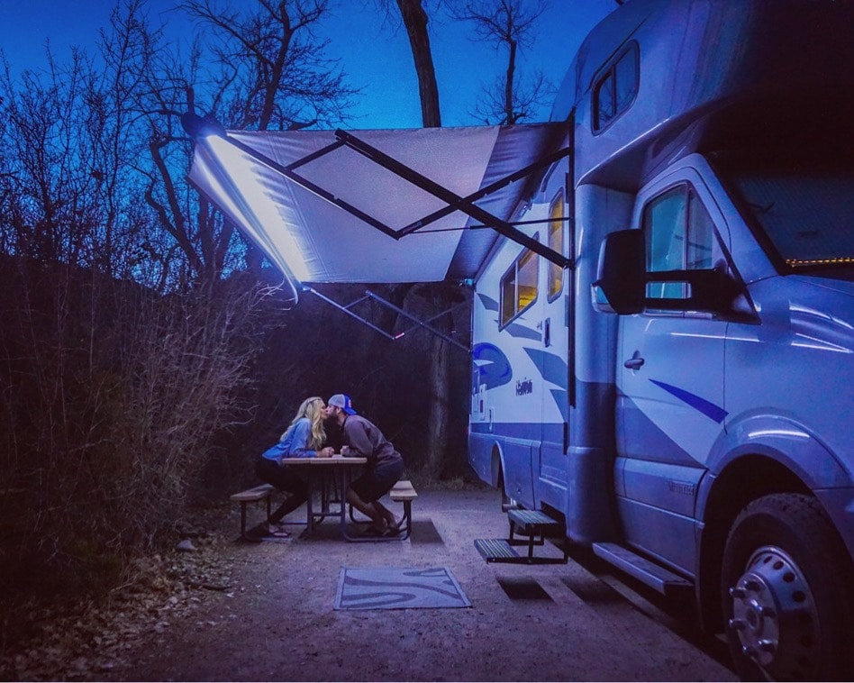 couple kissing under awning of motorhome RV