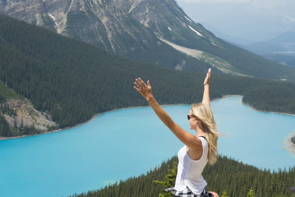 woman with arms raised at peyto lake in canada