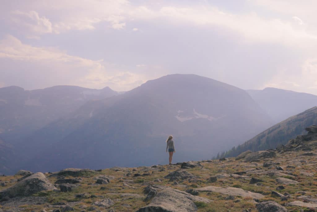 woman walking on top of mountain through the sunshine