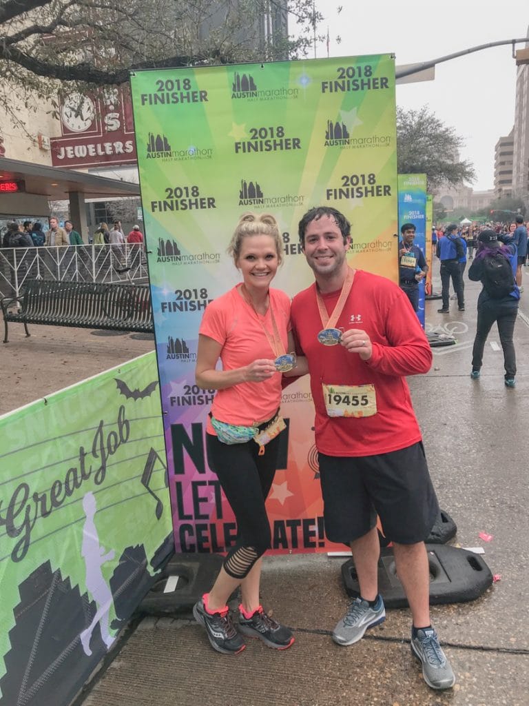 couple holding medals after completing the austin half marathon