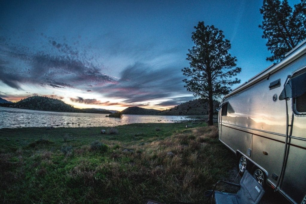 Airstream parked near lake with sunset
