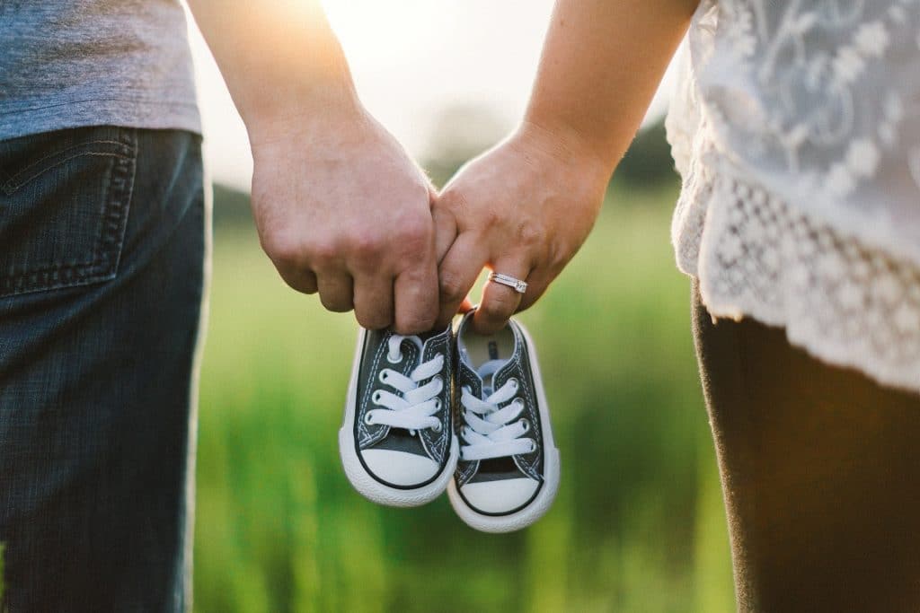 couple holding infant shoes in hands