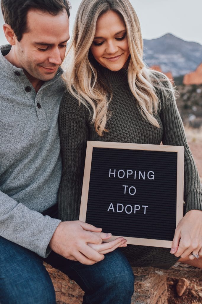 Couple holding board that says hoping to adopt