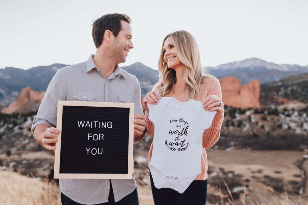 Adopting couple holding sign and onesie waiting for adoption