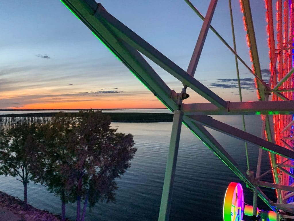 Ferris wheel overlooking a lake at sunset