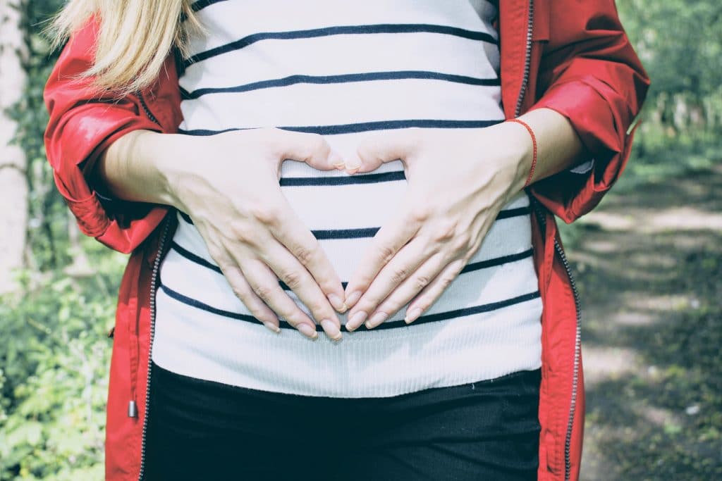 pregnant woman with hands in heart on belly