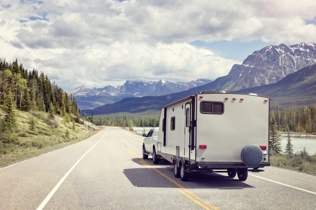 Truck pulling a travel trailer down a scenic mountain road