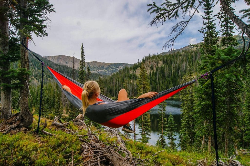 girl sitting in a hammock overlooking mountains and river