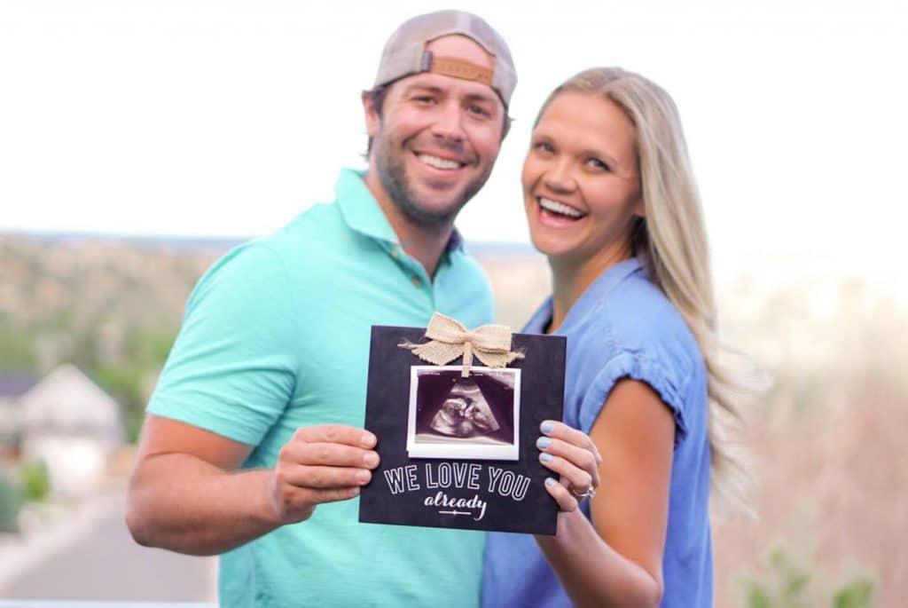 Couple holding ultrasound photo to share infant adoption announcement