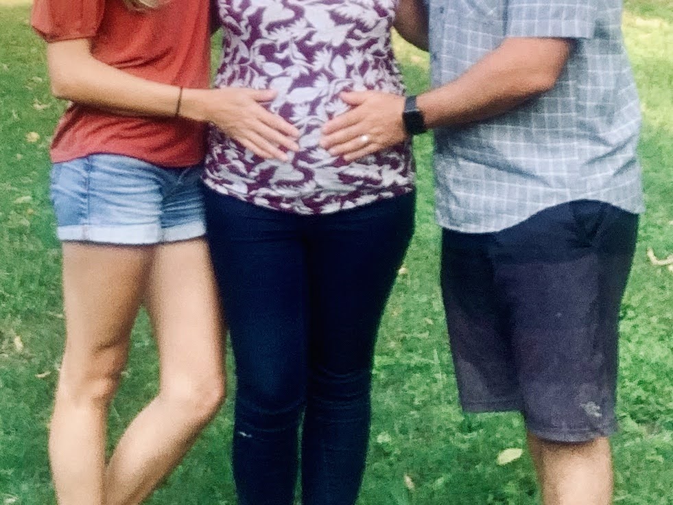 Adoptive couple putting hands on birth mom's pregnant belly