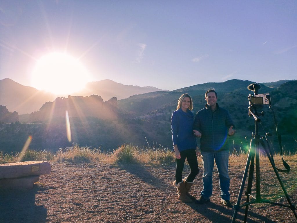 camera on a tripod filming a couple with beautiful mountain scenery behind them