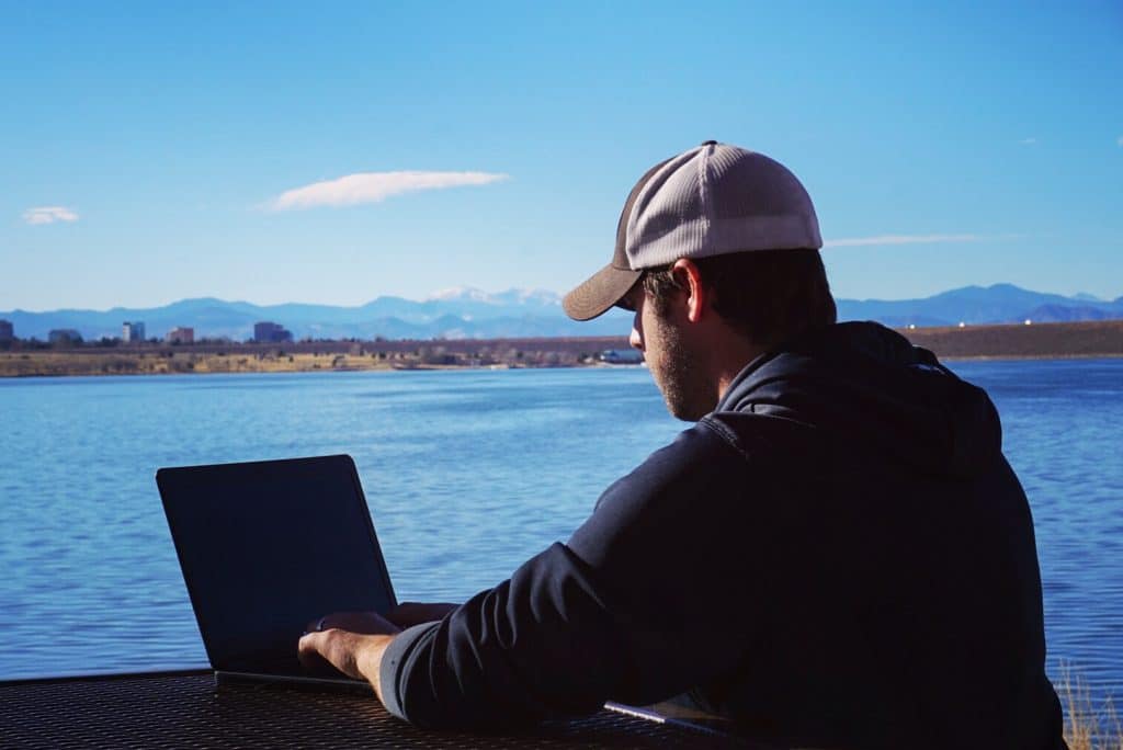 man working on a laptop overlooking lake