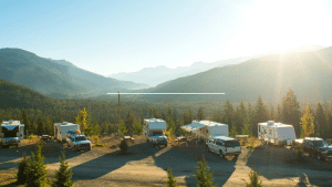 Different RVs parked at a campground with mountain views as the sun sets