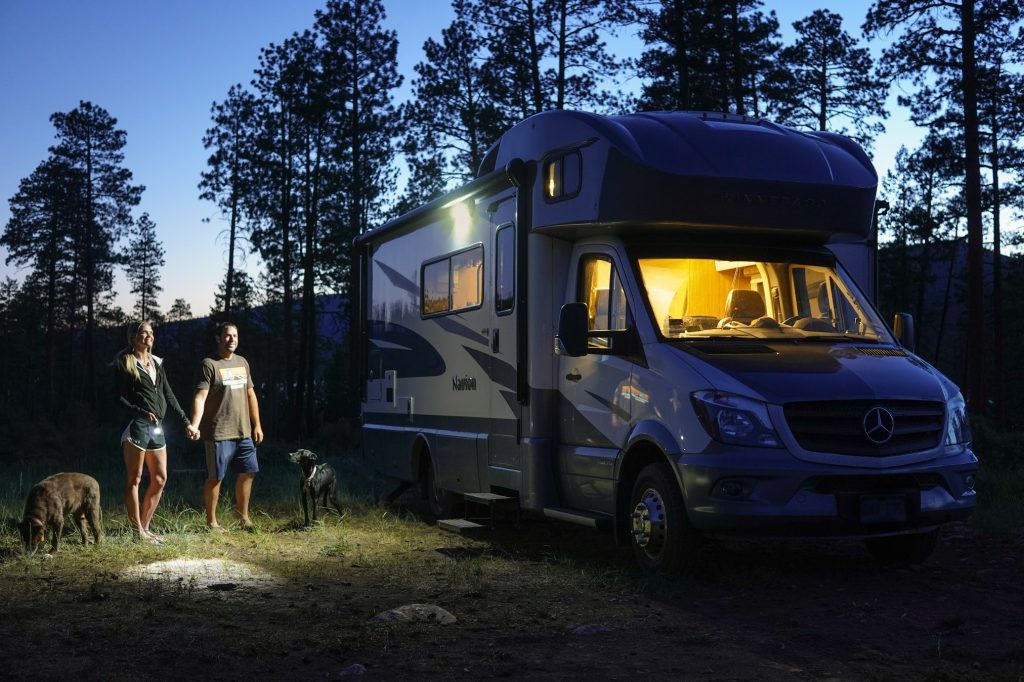 Couple standing in dark next to lit up RV