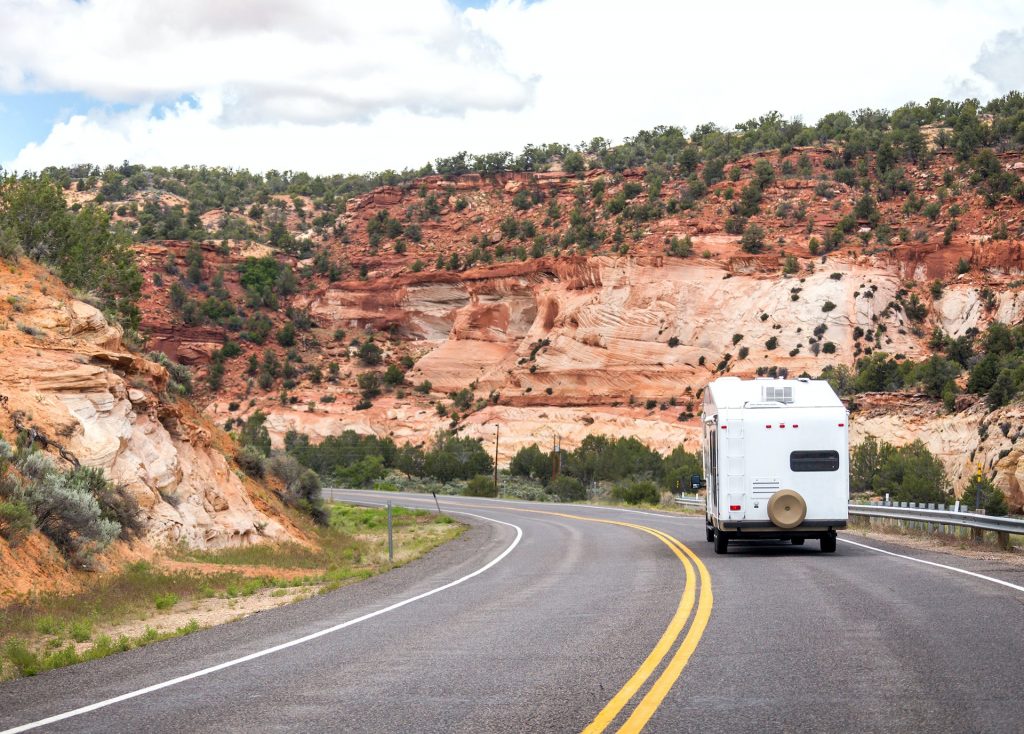 back view of an RV trailer being pulled down desert road